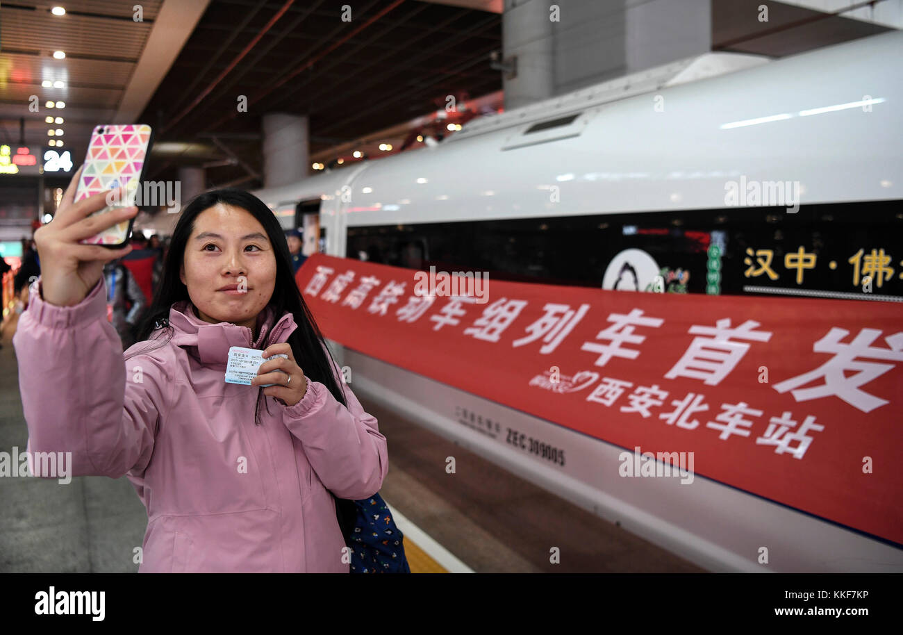 XI'an. 6 dicembre 2017. Un turista si cimenta accanto al primo treno ad alta velocità da Xi'an a Chengdu a sud-ovest della Cina presso la stazione ferroviaria nord di Xi'an a Xi'an, capitale della provincia di Shaanxi, il 6 dicembre. 2017. La linea ferroviaria ad alta velocità che collega Xi'an e Chengdu, capitale della provincia di Sichuan, è entrata in funzione mercoledì, riducendo il tempo di percorrenza tra le due città da circa 11 ore a sole 4 ore. Crediti: Tao Ming/Xinhua/Alamy Live News Foto Stock