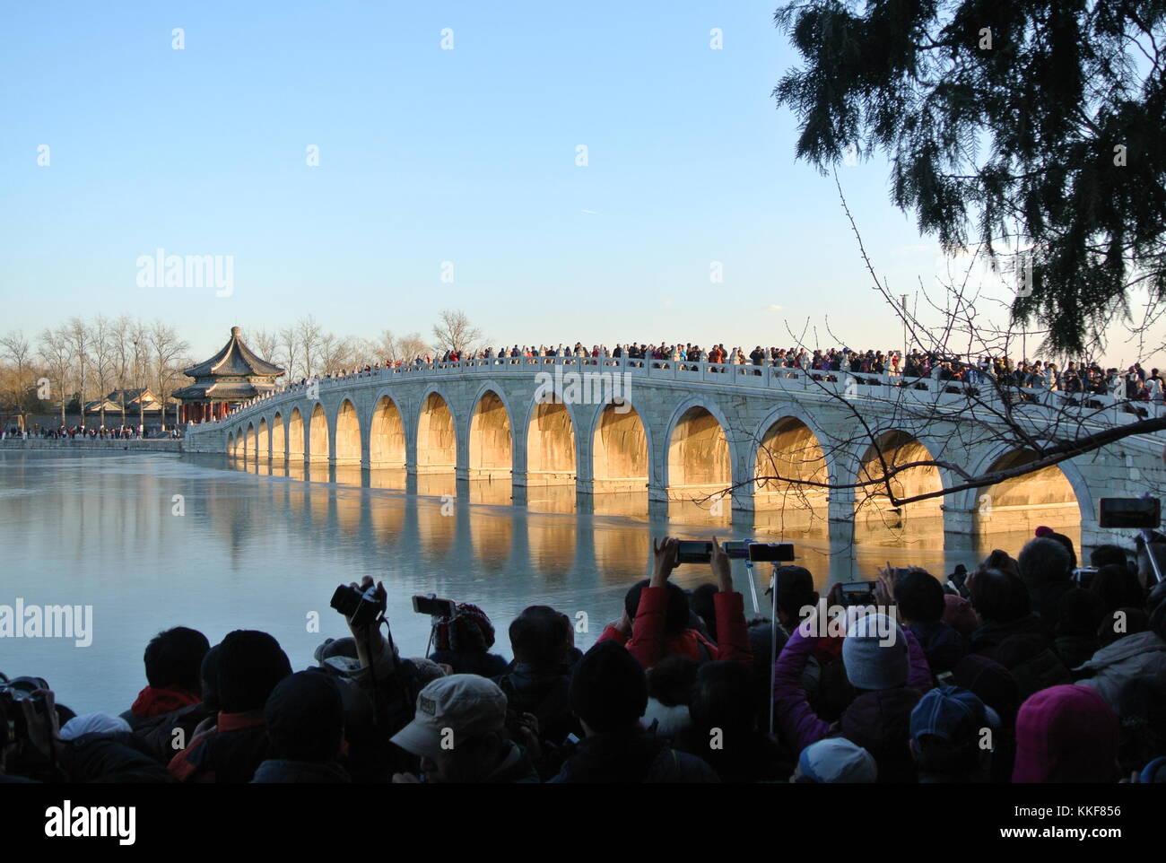Pechino, Cina. 6 dicembre 2017. I visitatori ammirano il paesaggio del crepuscolo che splende attraverso il ponte del diciassettesimo arco nel Palazzo d'Estate di Pechino, capitale della Cina, il 6 dicembre 2017. Credito: Ma Zhihong/Xinhua/Alamy Live News Foto Stock