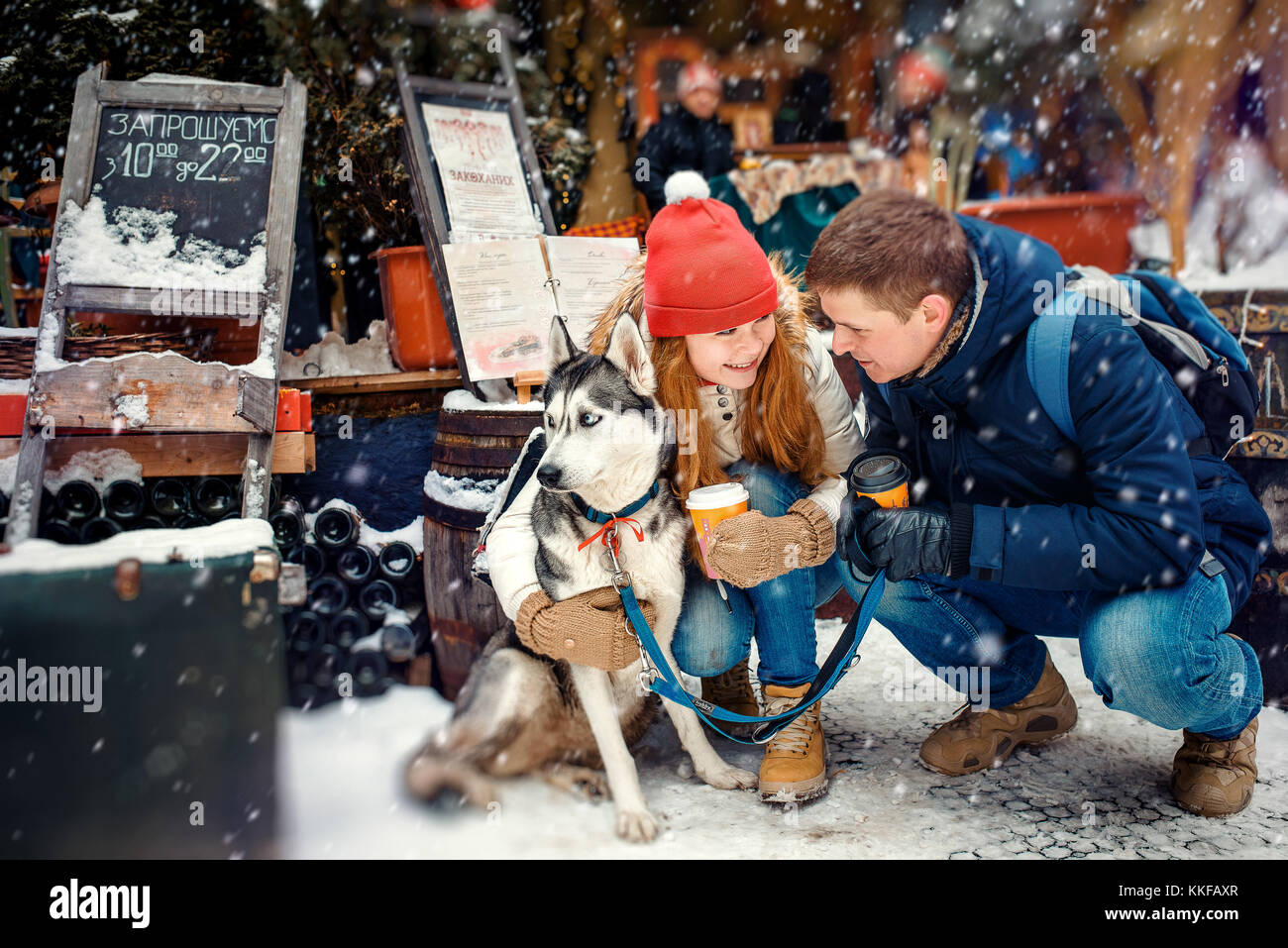 Felice bella giovane di bere il tè del caffè all'aperto avvolgente siberian husky nevicata cityscape. Foto Stock