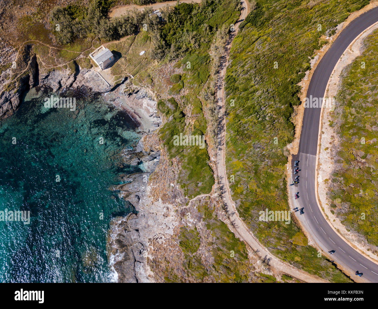 Vista aerea della costa della Corsica, strade tortuose e insenature con il mare cristallino. motociclisti parcheggiato sul bordo di una strada. cap Corse francia Foto Stock