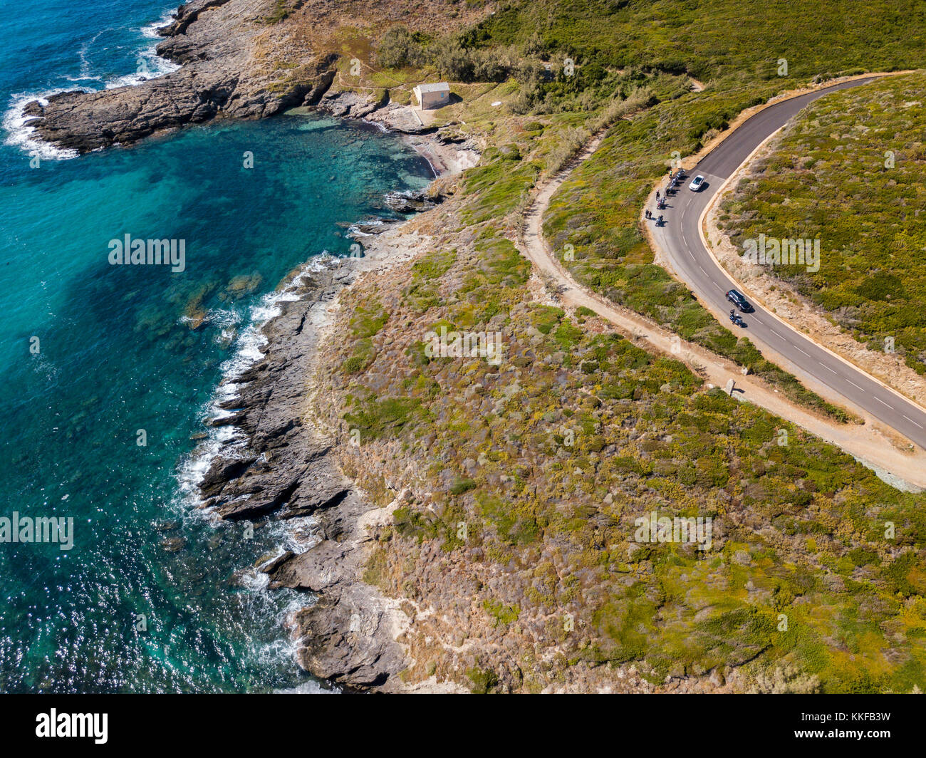 Vista aerea della costa della Corsica, strade tortuose e insenature con il mare cristallino. motociclisti parcheggiato sul bordo di una strada. cap Corse francia Foto Stock