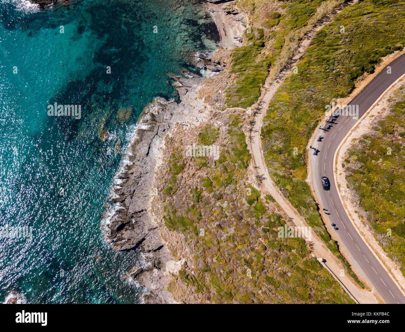 Vista aerea della costa della Corsica, strade tortuose e insenature con il mare cristallino. motociclisti parcheggiato sul bordo di una strada. cap Corse francia Foto Stock
