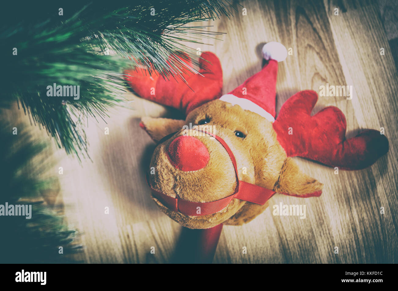 Stick di peluche giocattolo di renne su pavimento di legno vicino ad albero di Natale a casa Foto Stock