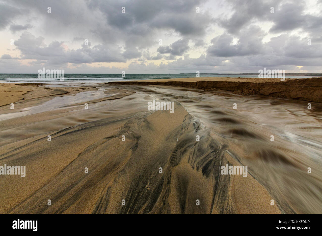 Il flusso di sabbia come le gare di acqua verso il mare aperto dopo il taglio di un canale in sabbia a Carbis Bay in West Cornwall, nel sud ovest dell'inghilterra. Foto Stock