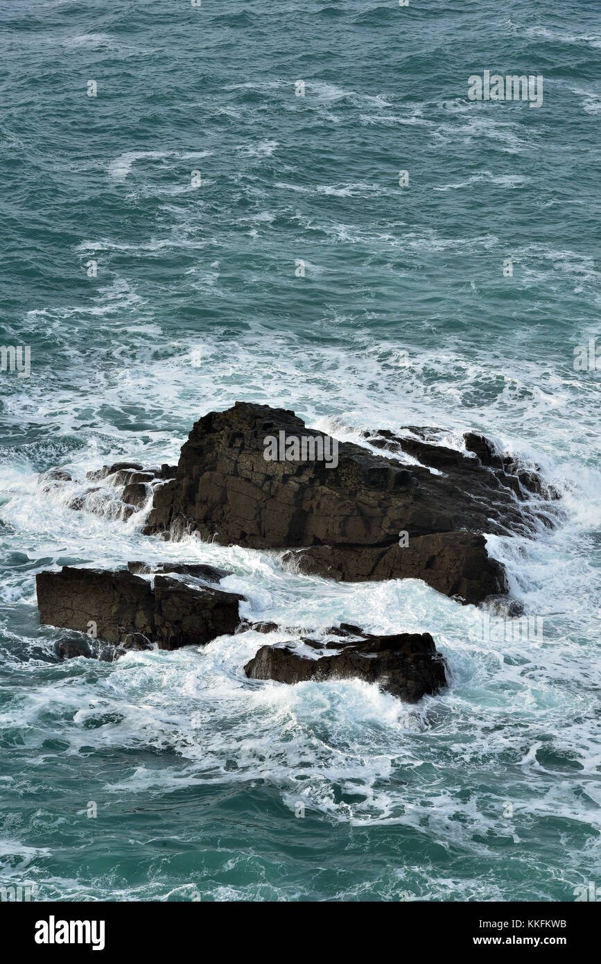 Alcune rocce frastagliate sulla North Cornish Coast fuori dell'acqua e coperto con le onde e spray. Robusto cornish paesaggi costieri. Foto Stock