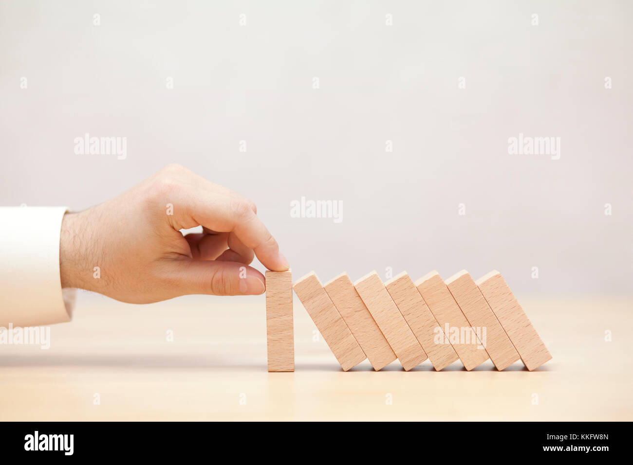 Mano d'uomo fermare l' effetto domino. Concetto di immagine per la strategia commerciale e la soluzione delle crisi. Foto Stock