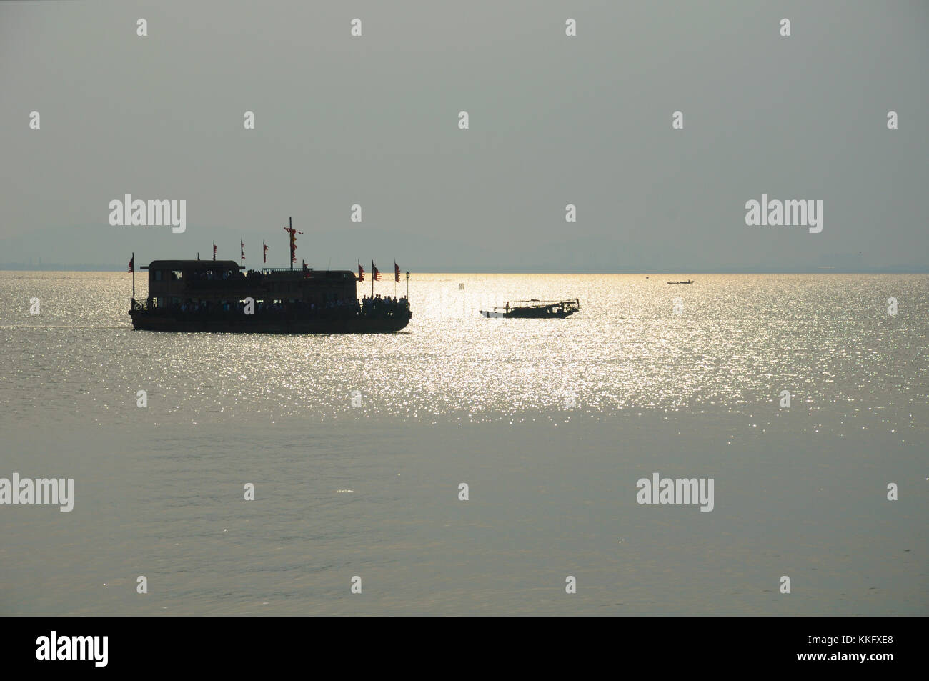 Una silohuette di una barca turistica e la pesca in barca sulle acque del Lago Tai, Taihu al di fuori dei tre regni city scenic area di Wuxi in Cina Jiang Foto Stock