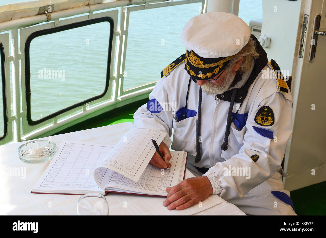 Il vecchio capitano esperto riempie il giornale di bordo dopo la navigazione della nave Foto Stock