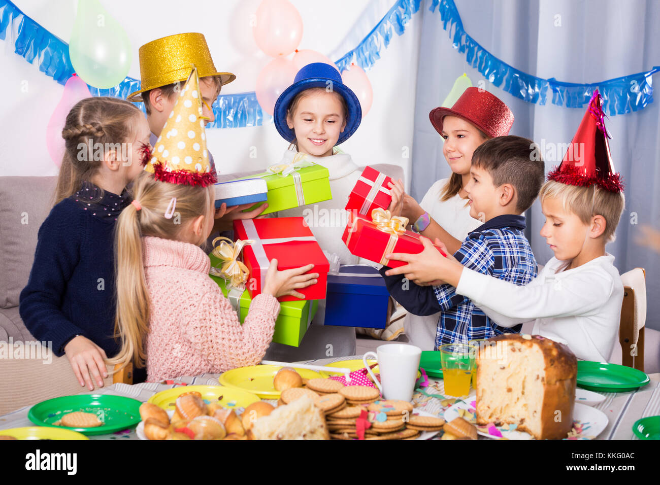 Dei bambini felici presentando doni alla bambina durante la festa di compleanno Foto Stock