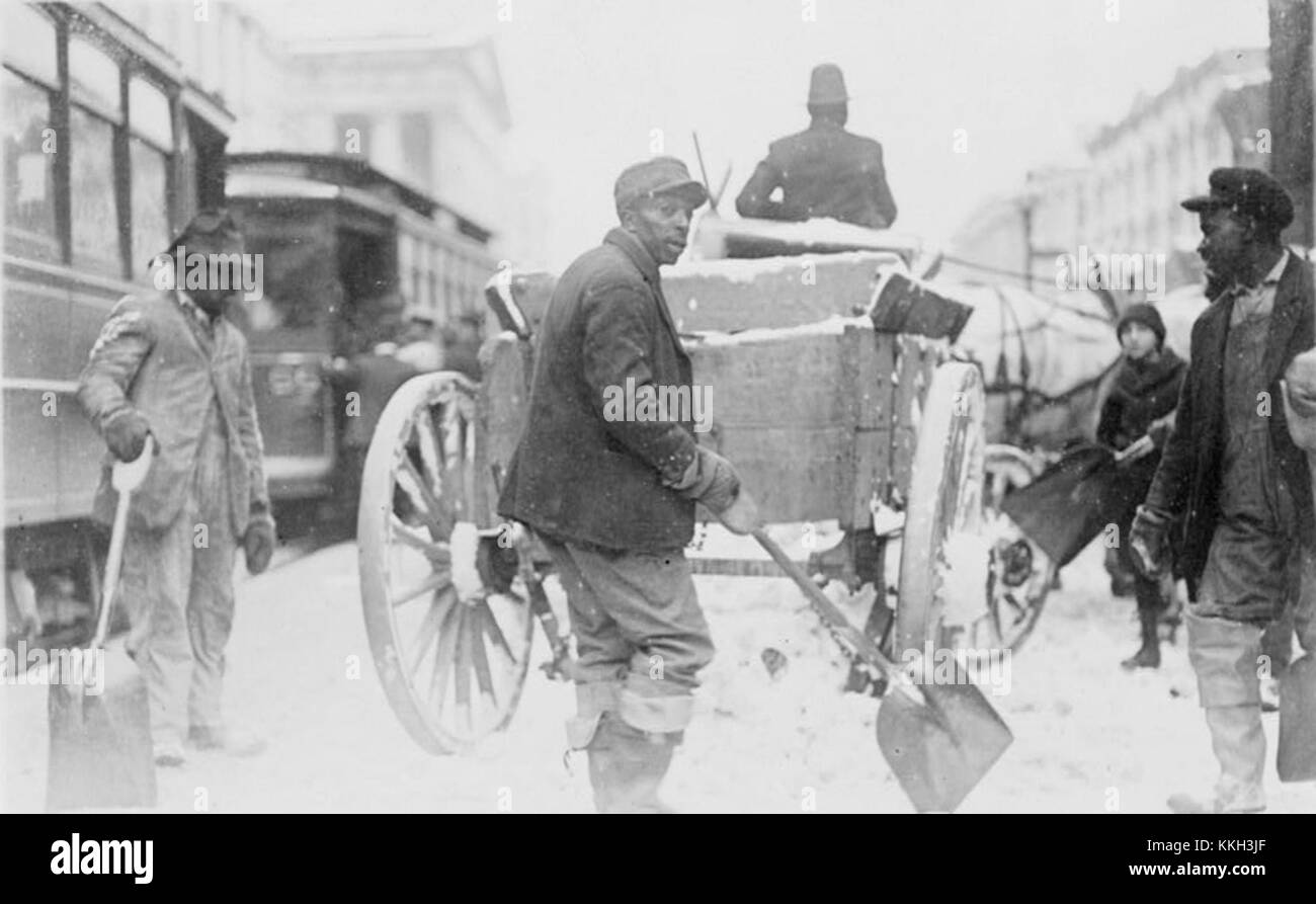 Questa fotografia raffigura uomini afroamericani che spalancano la neve su una strada durante i mesi invernali. Mette in evidenza la resilienza e il duro lavoro degli individui in condizioni meteorologiche difficili. Foto Stock