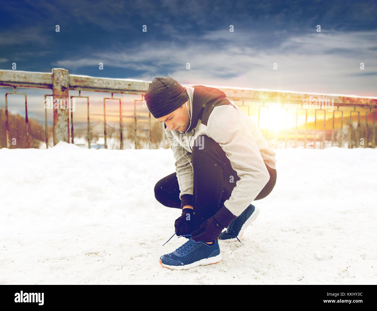 Uomo con gli auricolari legatura di calzature sportive in inverno Foto Stock