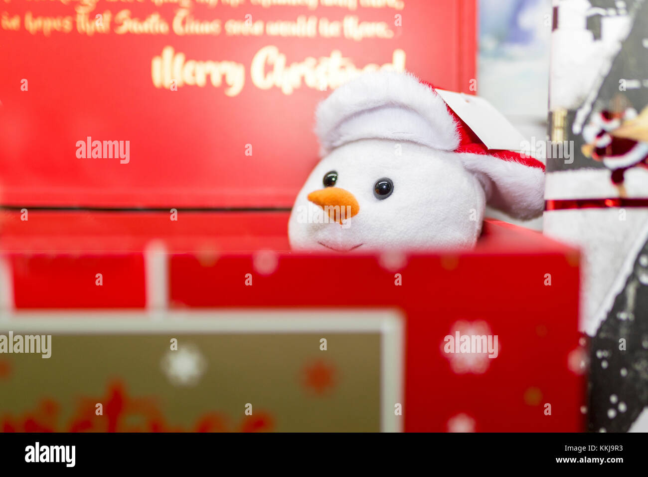 Festive morbido peluche pupazzo di neve che spuntavano di un rosso Natale scatola regalo in un negozio di visualizzare NEL REGNO UNITO Foto Stock