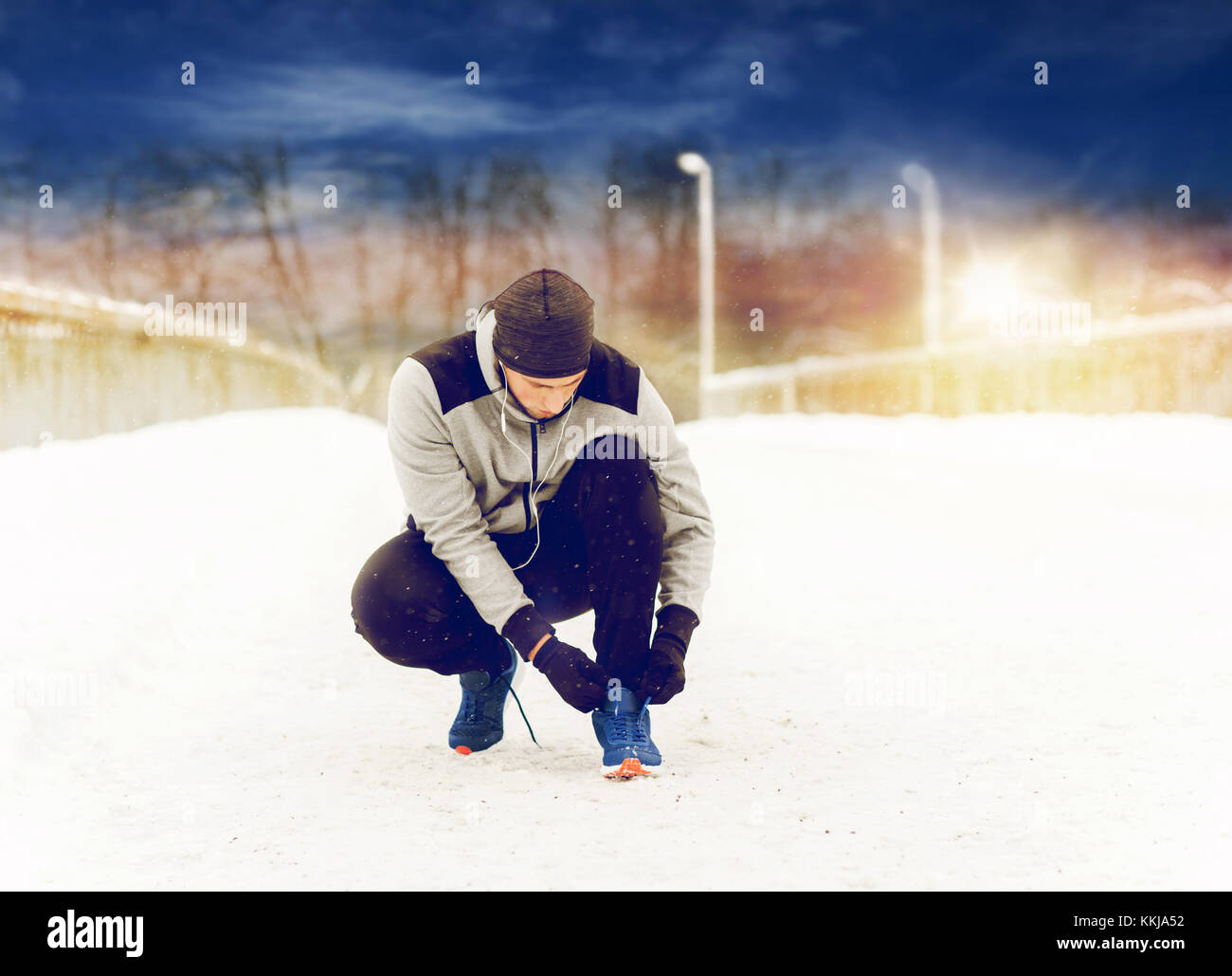 Uomo con gli auricolari la legatura calzatura sportiva in inverno Foto Stock