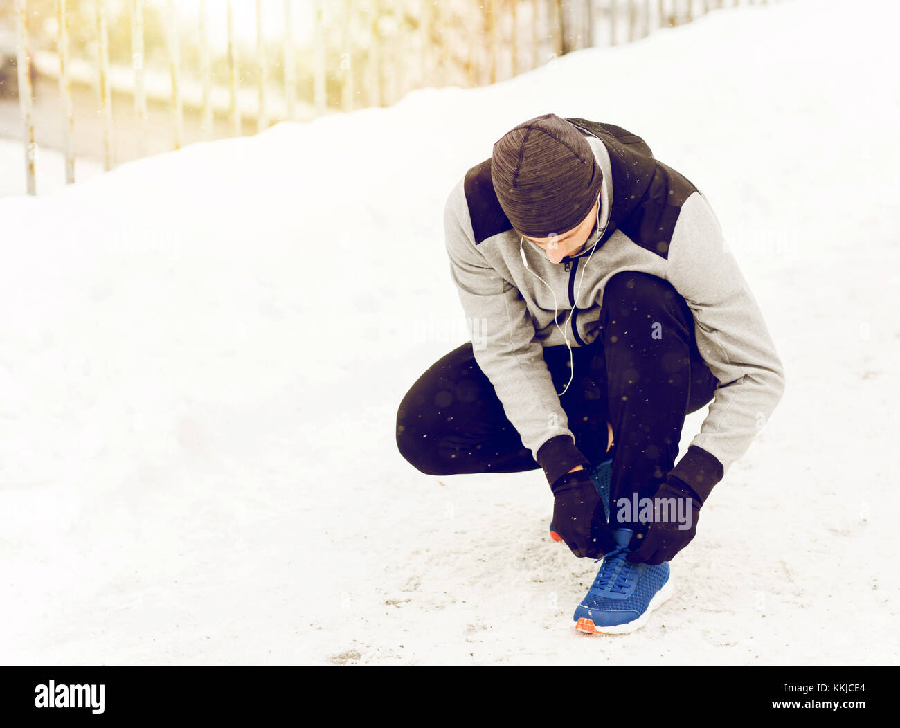 Uomo con gli auricolari la legatura calzatura sportiva in inverno Foto Stock