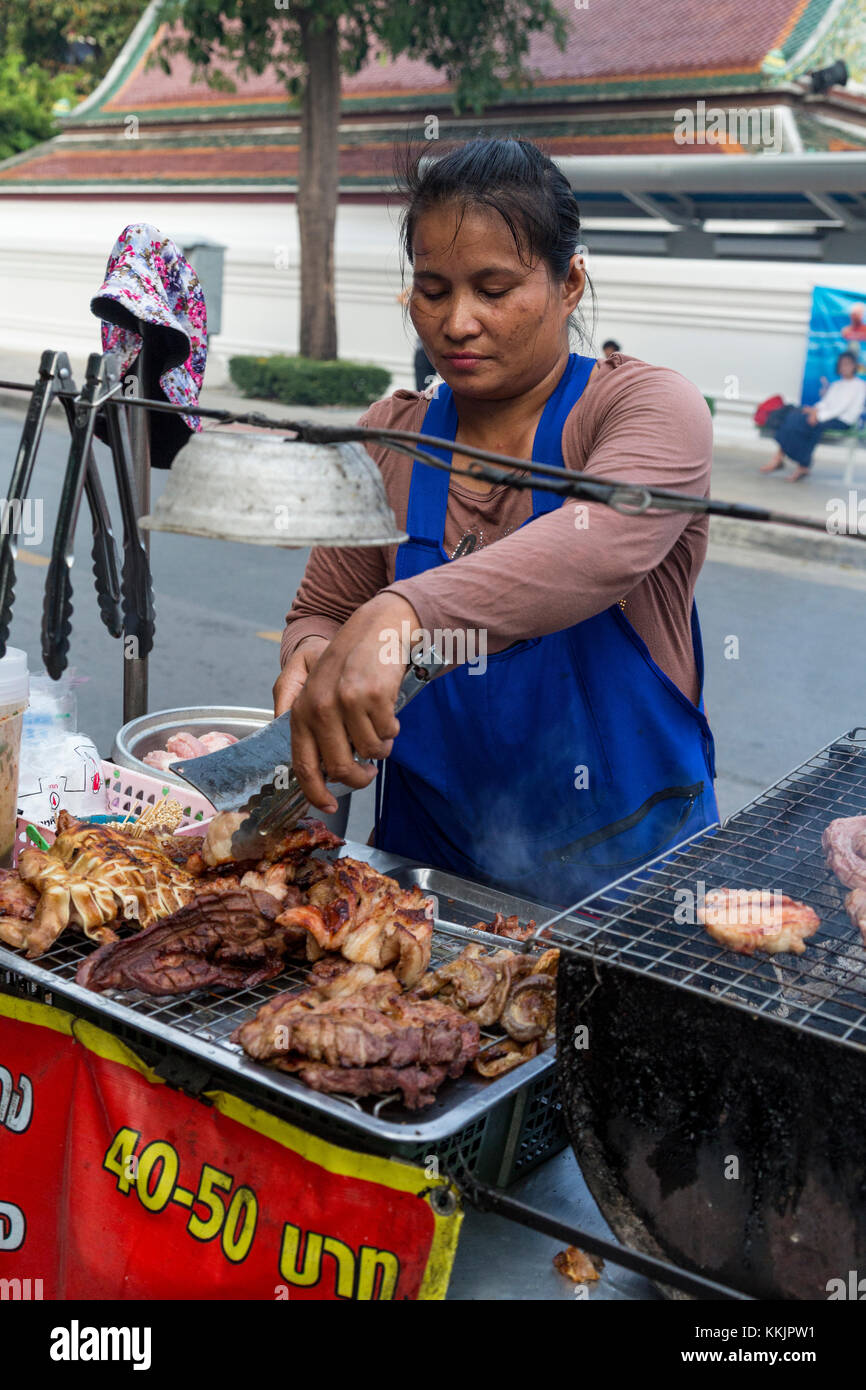 Bangkok, Tailandia. Cucina di strada produttore presso il suo stand. Foto Stock