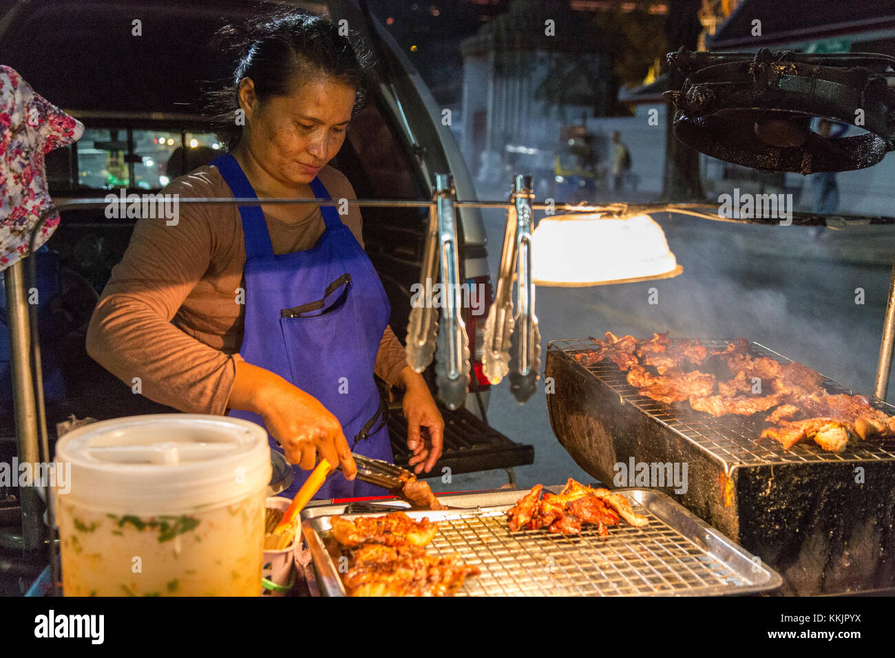 Bangkok, Tailandia. Cucina di strada produttore presso il suo stand durante la notte. Foto Stock