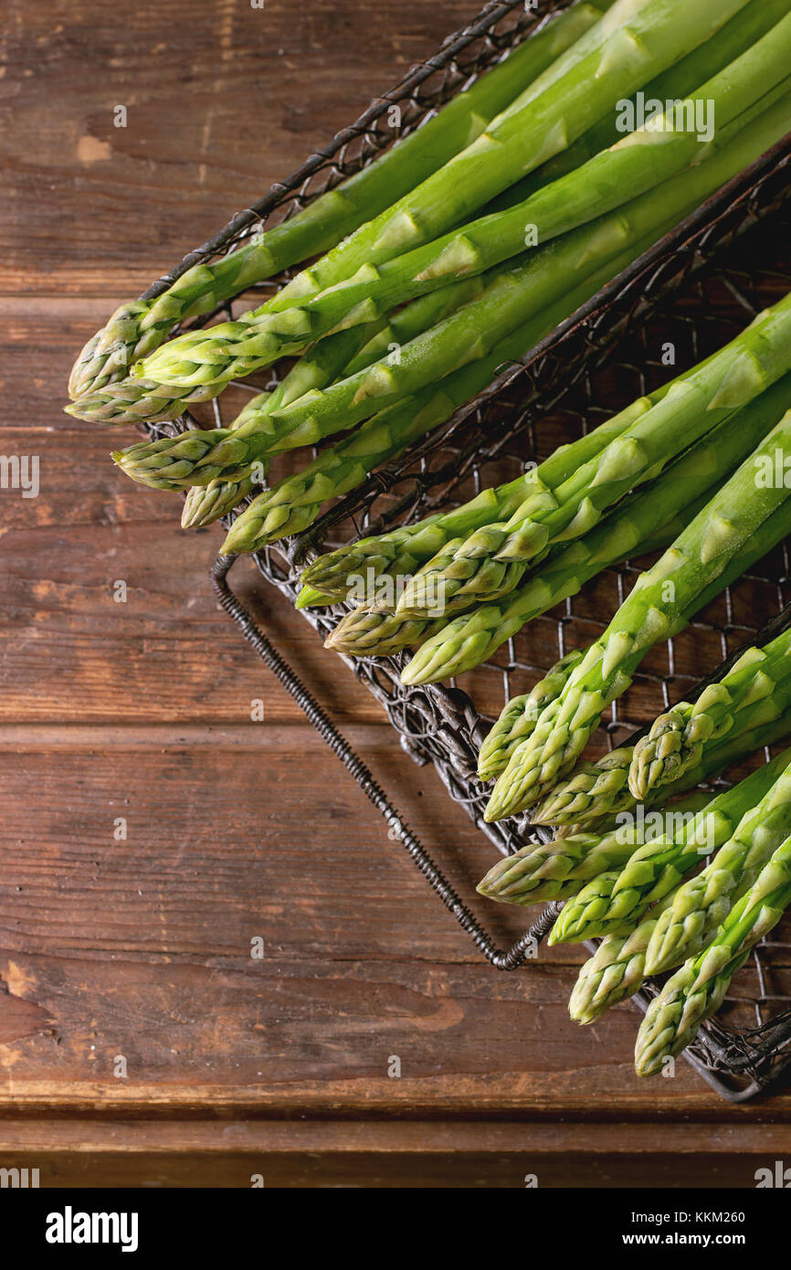 Gli asparagi verdi in metallo vintage scatola a griglia su un tavolo di legno. vista dall'alto. oscura atmosfera rustica. Foto Stock