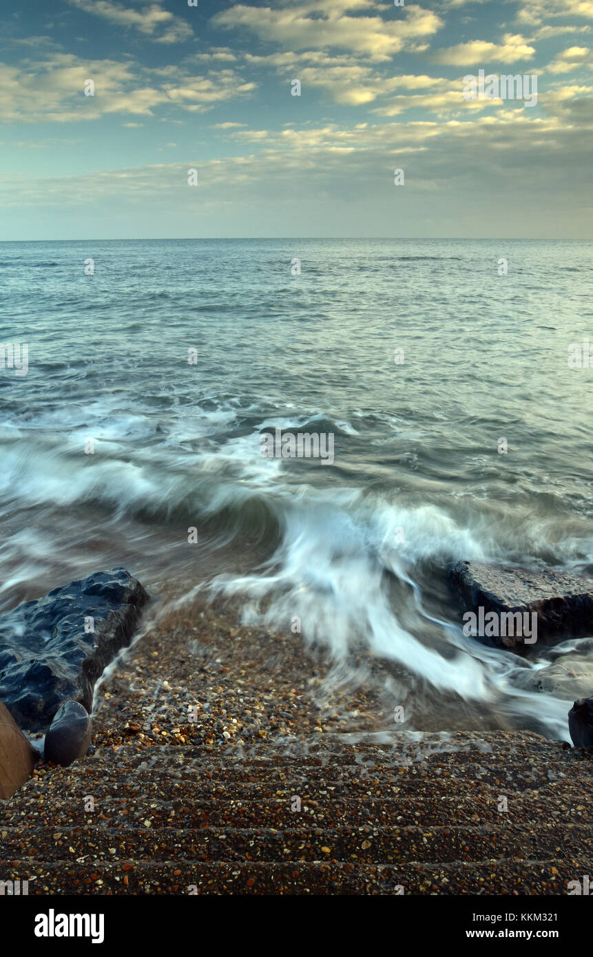 Lavaggio onde su roccia su una rocciosa e frastagliata linea costiera in un suggestivo paesaggio marino nell'isola di Wight, Regno Unito. calmante e rilassante sul paesaggio costiero. Foto Stock