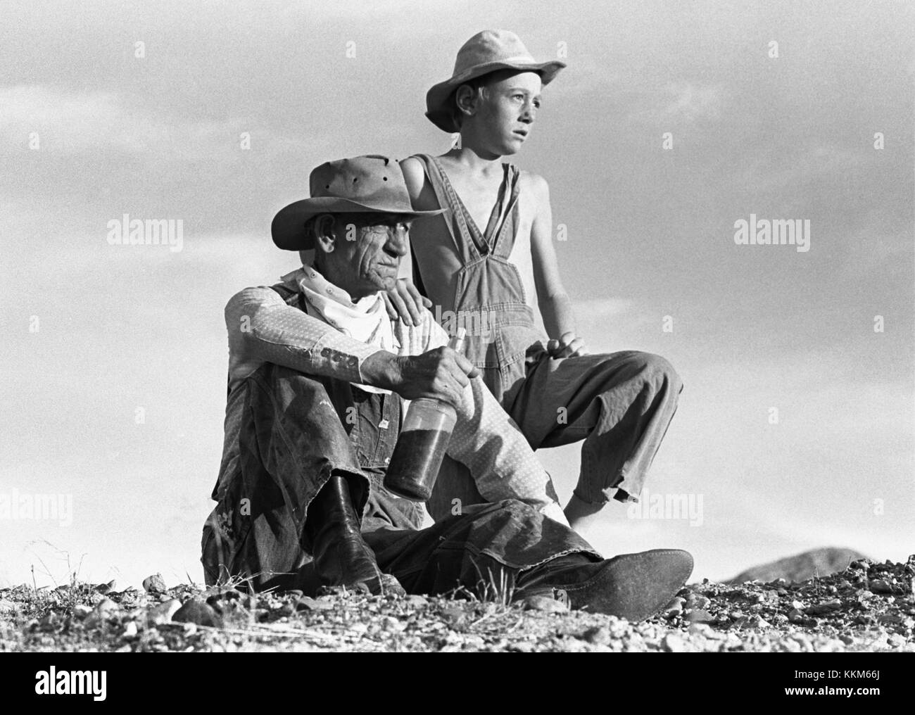 Ritratto di un vecchio manwith una bottiglia di whiskey e un ragazzo seduto sulla cima di un colle, a circa 1940s Foto Stock