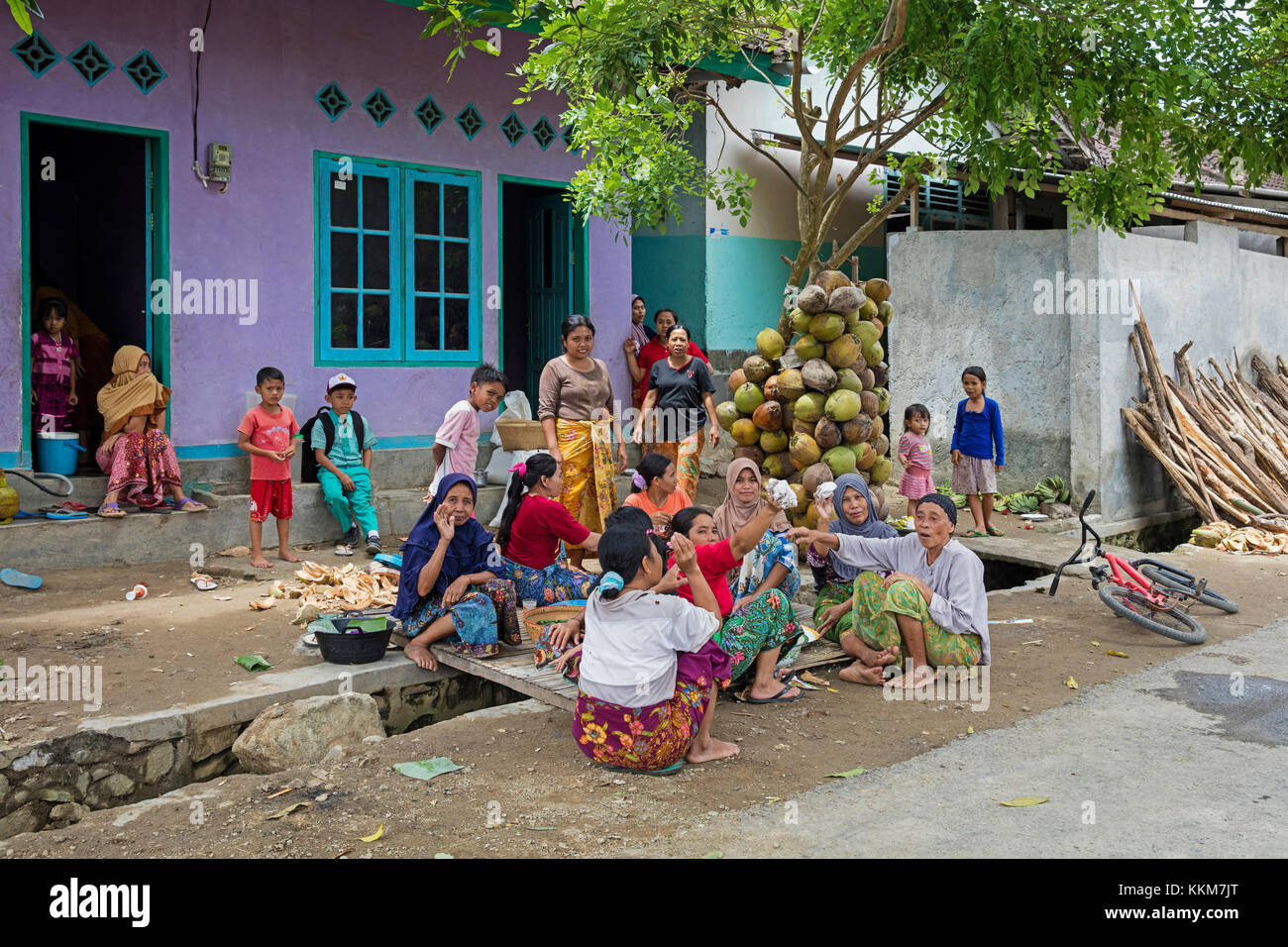 Indonesian donne e bambini nella preparazione degli alimenti mediante spremitura carne di noce di cocco in villaggio sull'Isola di Lombok, INDONESIA Foto Stock