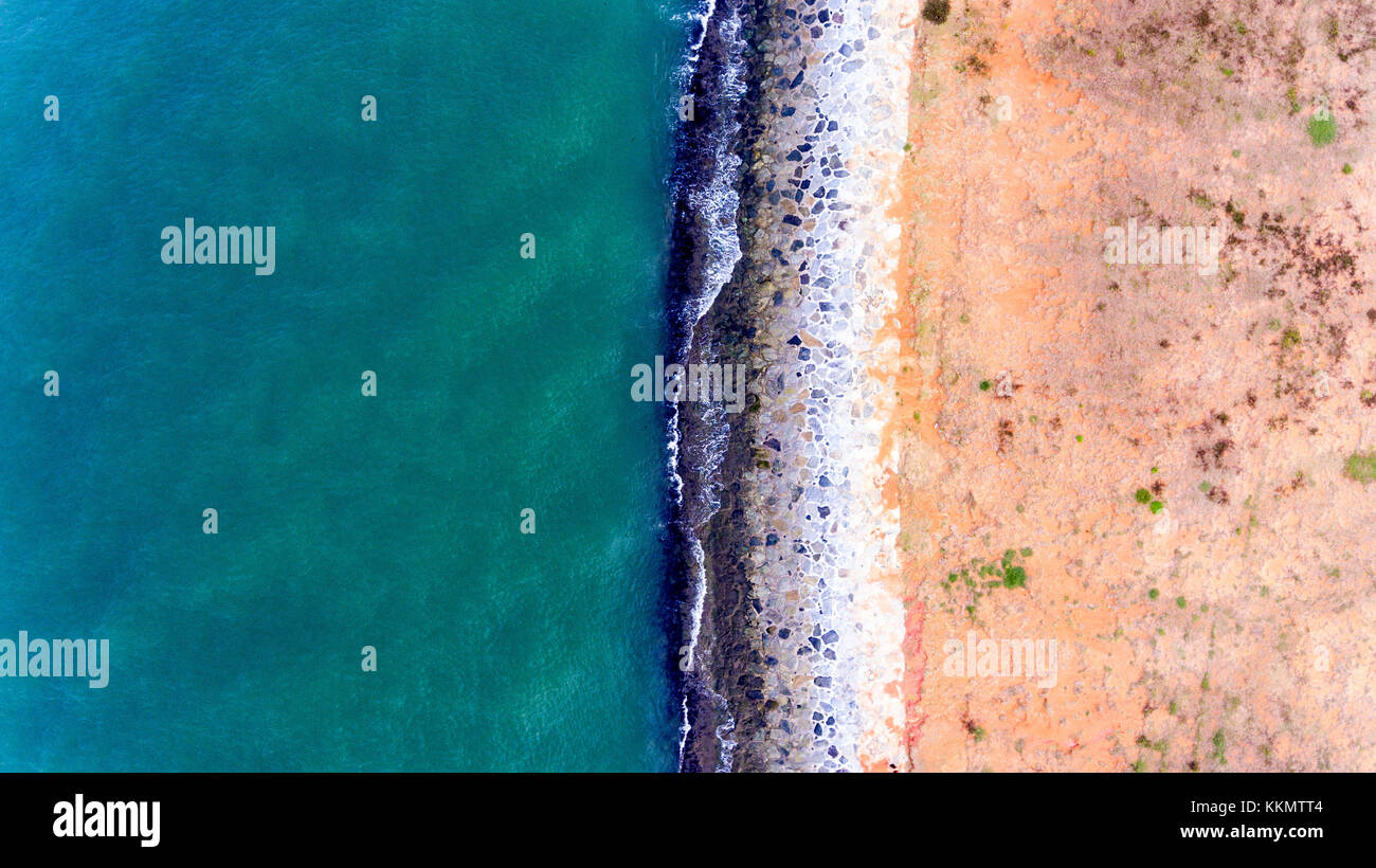 Acqua schiantarsi su una trama splendidamente spiaggia rocciosa. Foto Stock