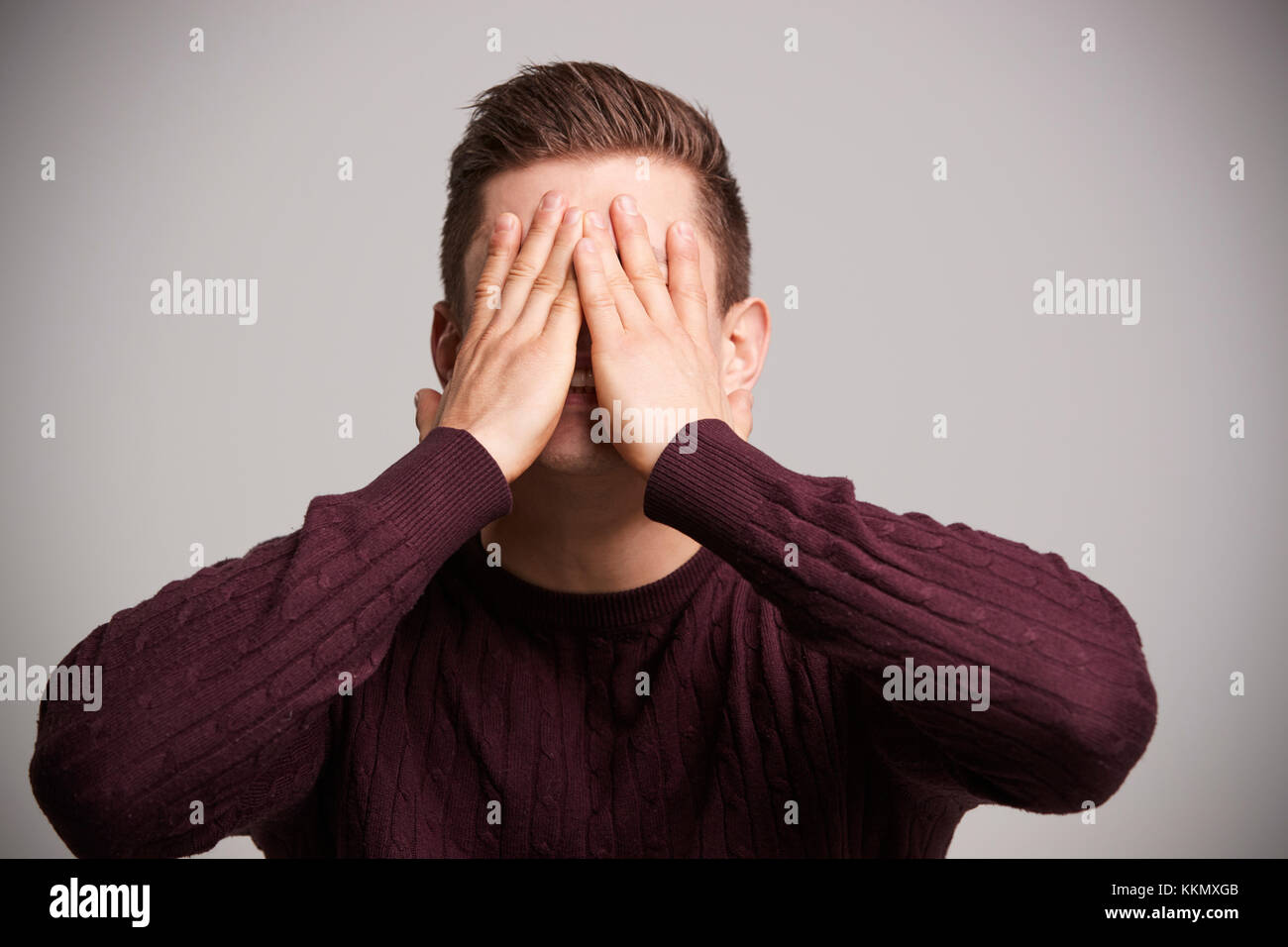 Ritratto di un giovane uomo bianco con le mani che coprono il suo volto Foto Stock
