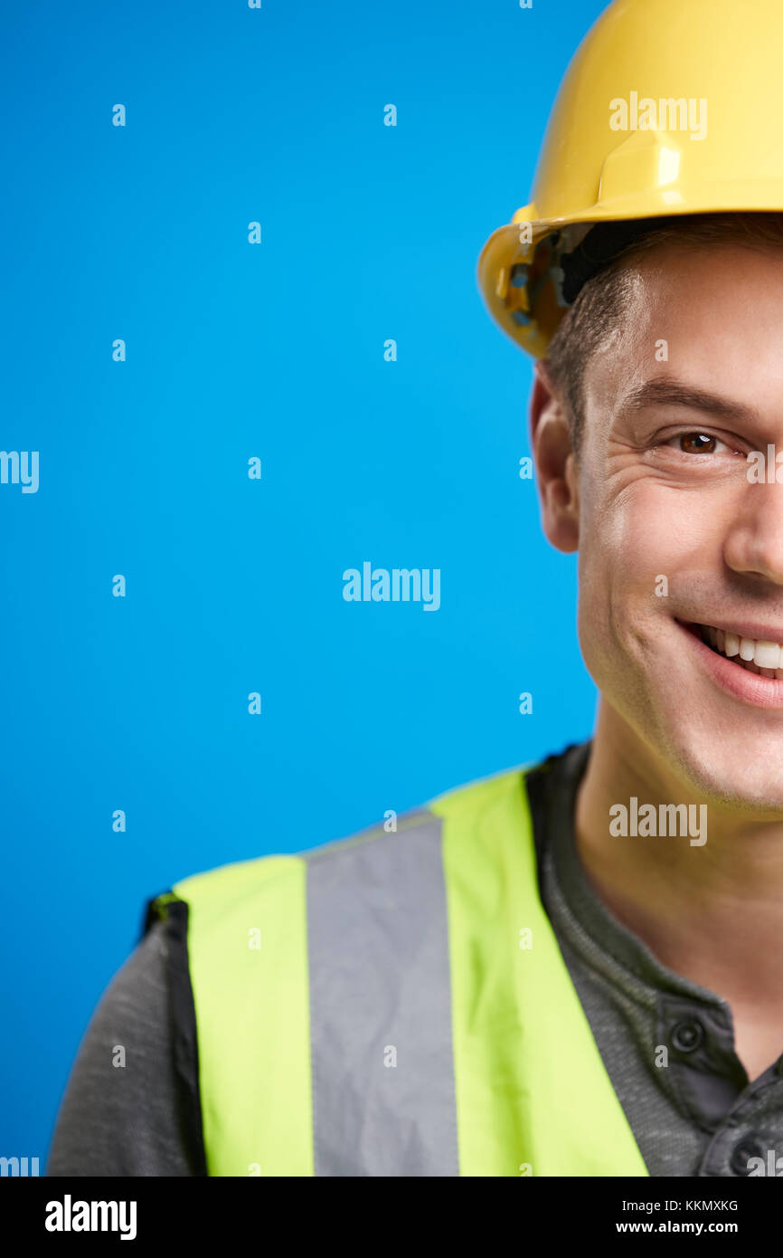 Sorridente giovane lavoratore edile in hard hat, raccolto verticale Foto Stock