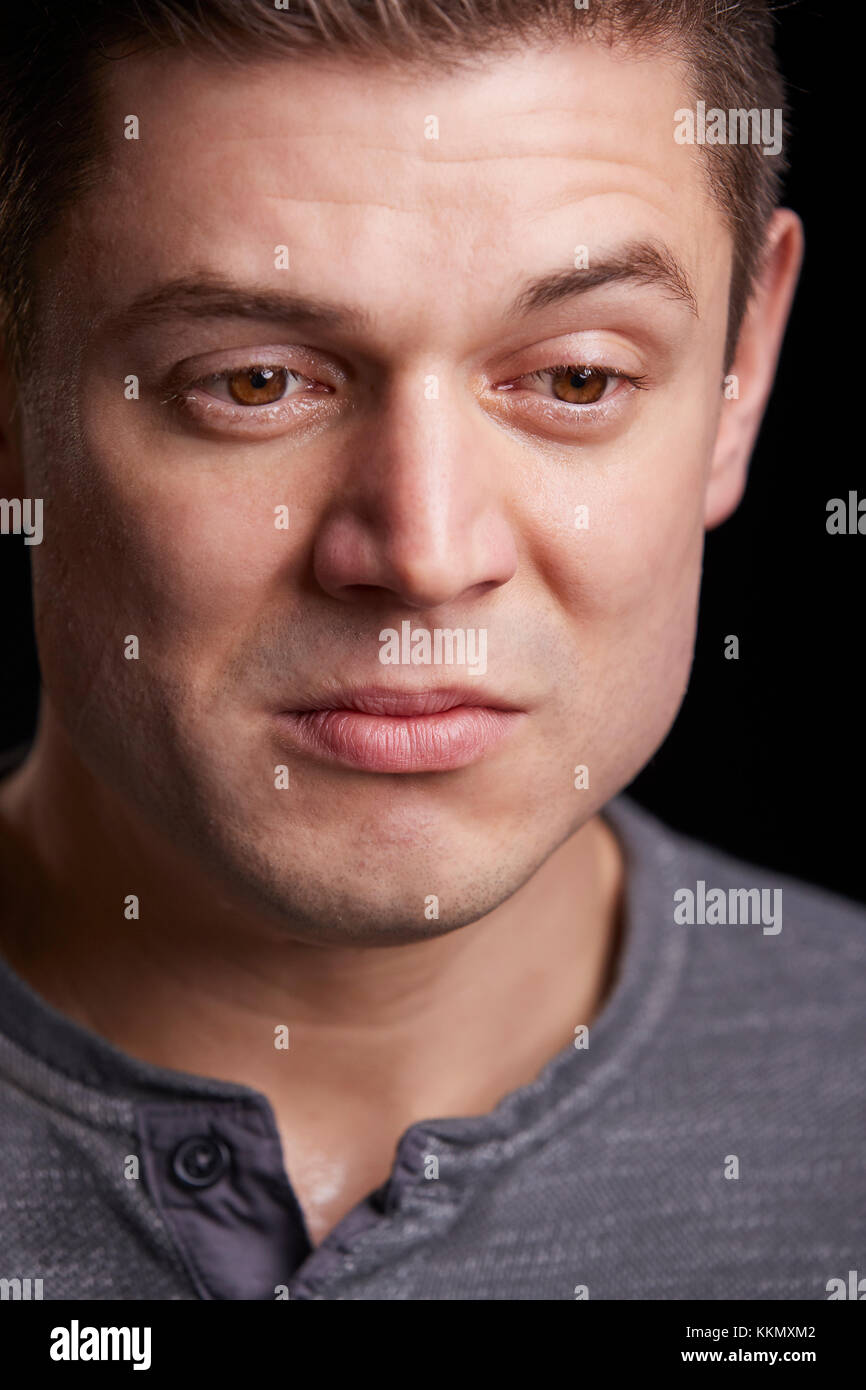 Ritratto verticale di pianto bianco giovane uomo che guarda in basso Foto Stock