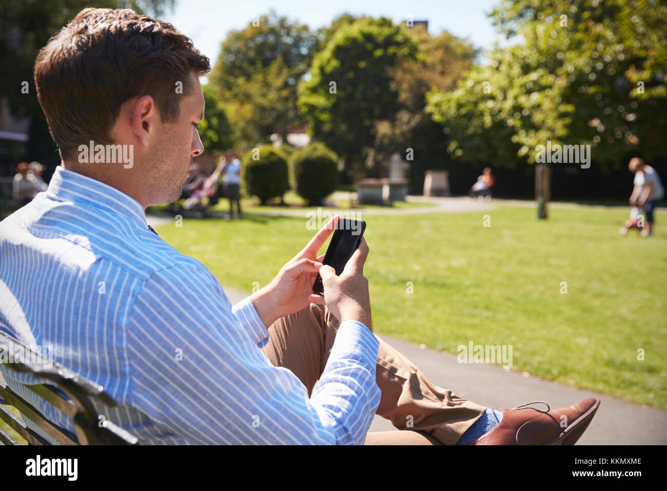Imprenditore all'esterno utilizzando il telefono cellulare sulla pausa pranzo in posizione di parcheggio Foto Stock