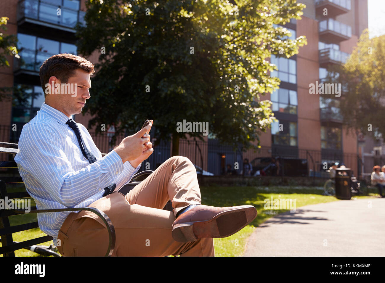 Imprenditore all'esterno utilizzando il telefono cellulare sulla pausa pranzo in posizione di parcheggio Foto Stock