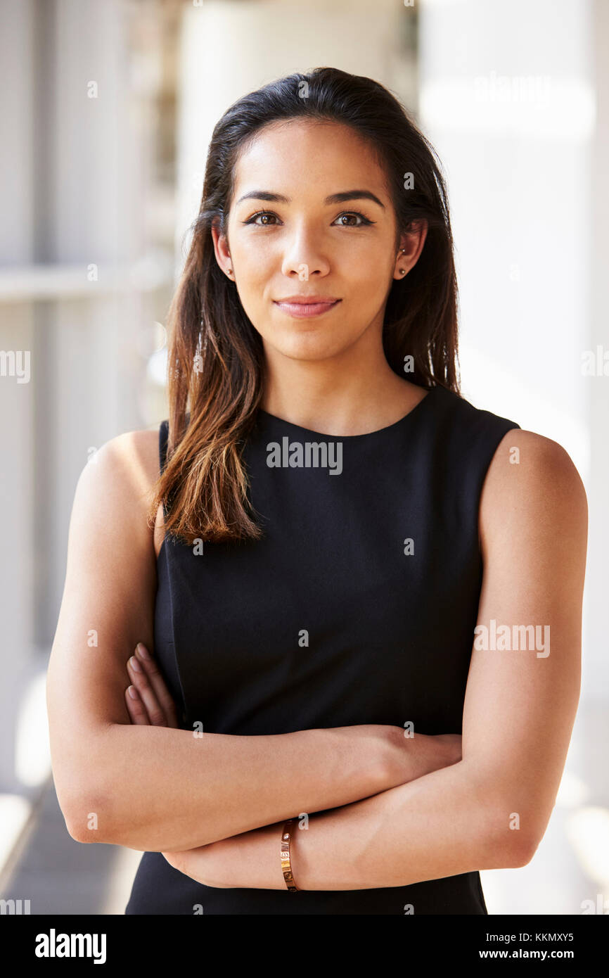 Ritratto di giovane donna che guarda alla telecamera con le braccia incrociate Foto Stock