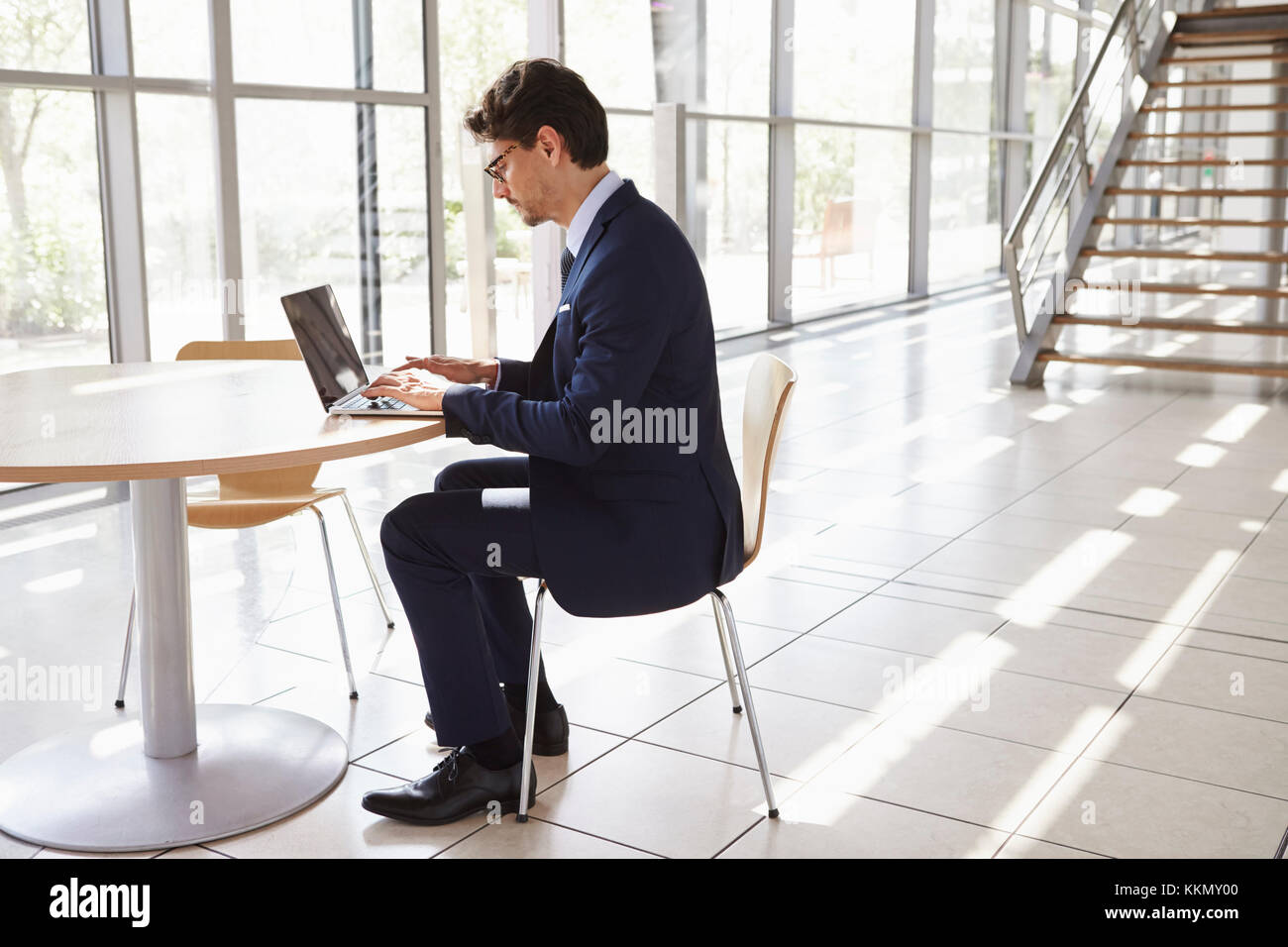 Giovane uomo professionale utilizzando laptop a piena lunghezza Foto Stock
