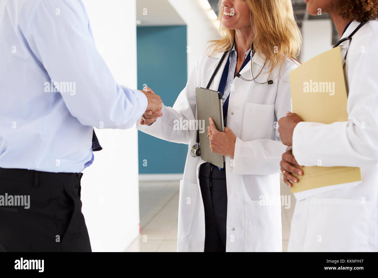 Tre maschi e femmine medici stringono le mani, metà sezione Foto Stock