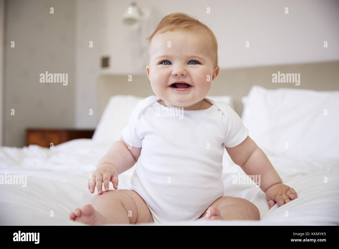 Happy Baby Boy seduta sul letto dei genitori Foto Stock
