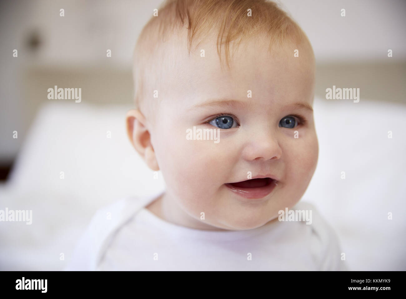 Close up Happy Baby Boy seduta sul letto dei genitori Foto Stock