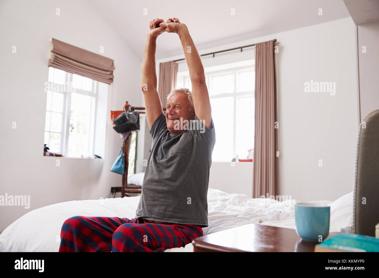 Senior uomo Svegliarsi e Stretching In camera da letto Foto Stock
