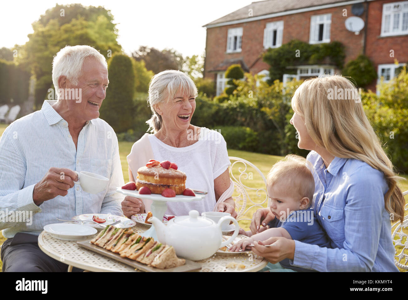 I nonni hanno il tè del pomeriggio con il nipote e figlia adulta Foto Stock