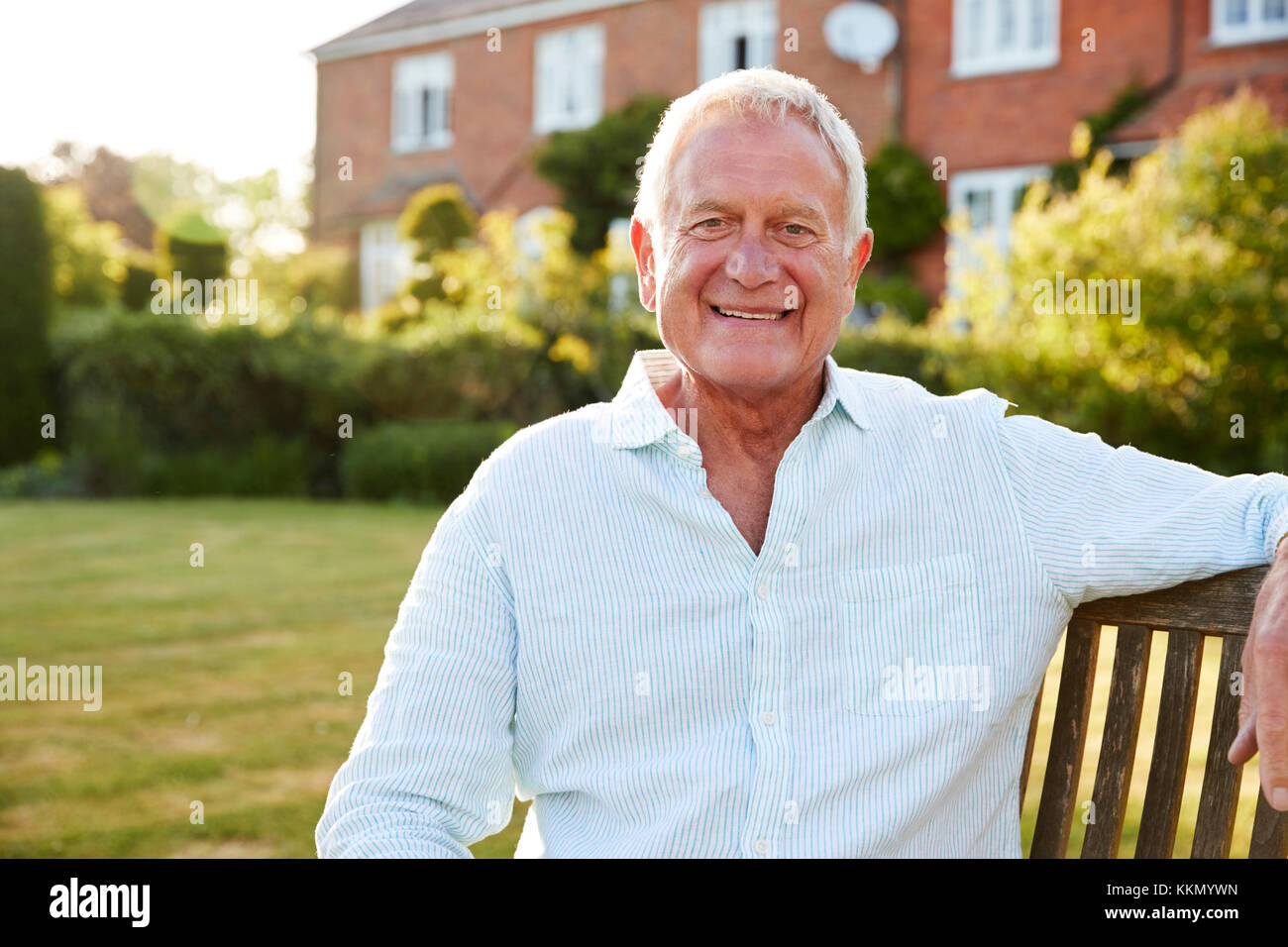 Senior uomo seduto sulla panchina da giardino in sera la luce solare Foto Stock