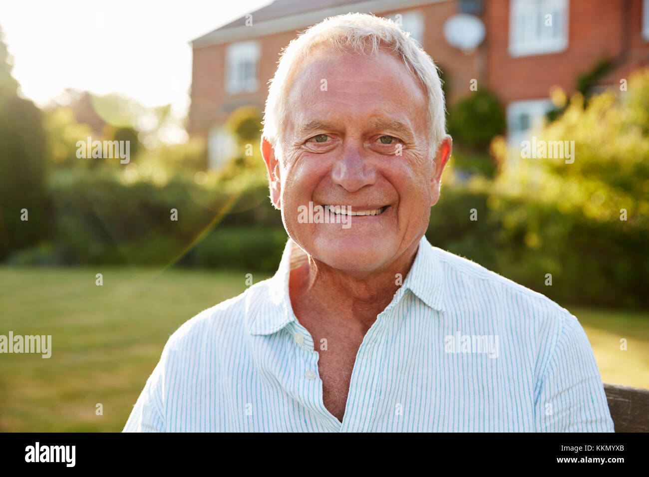 Senior uomo seduto sulla panchina da giardino in sera la luce solare Foto Stock