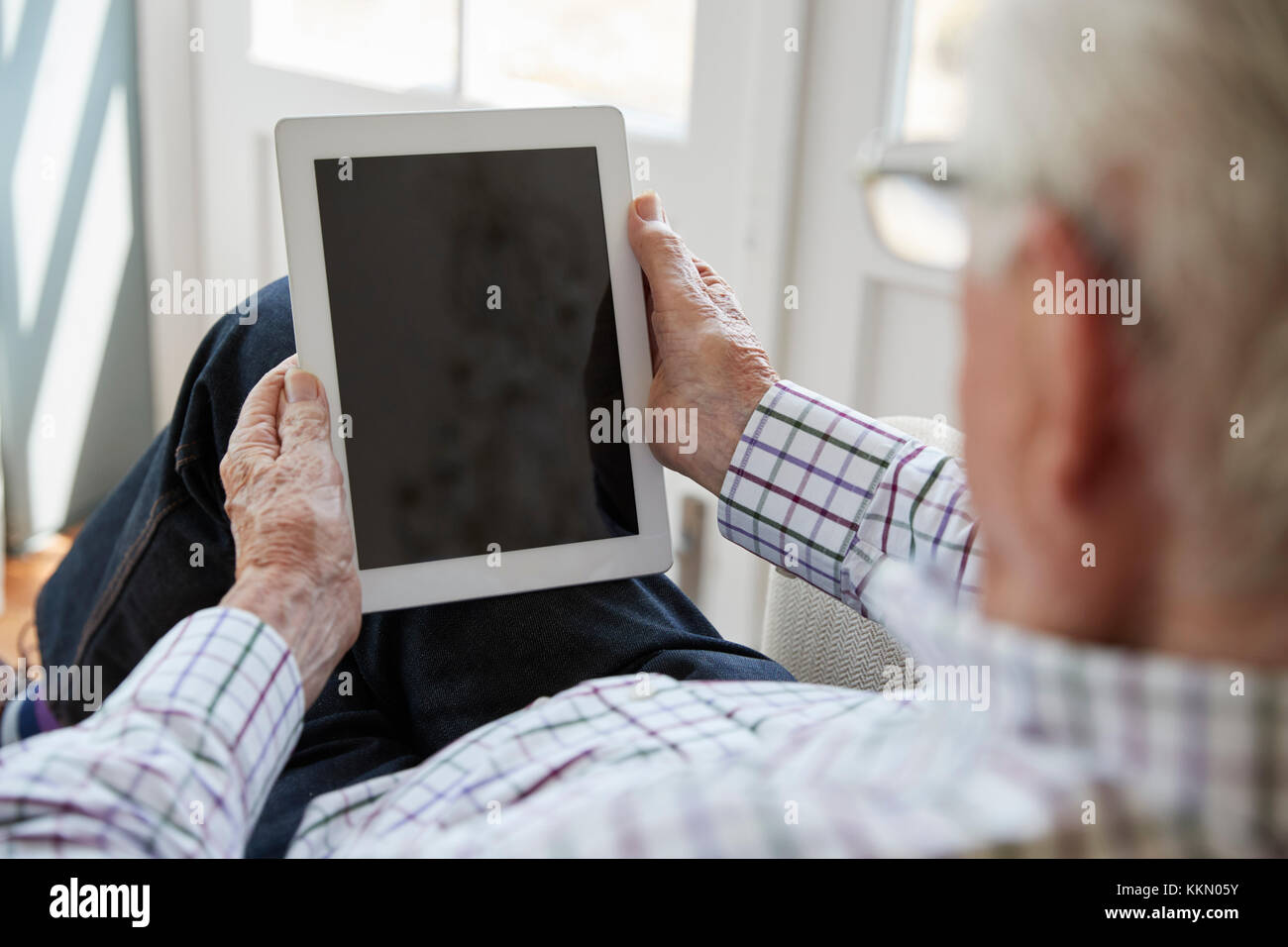 Senior uomo utilizzando computer tablet a casa, sulla spalla vista Foto Stock