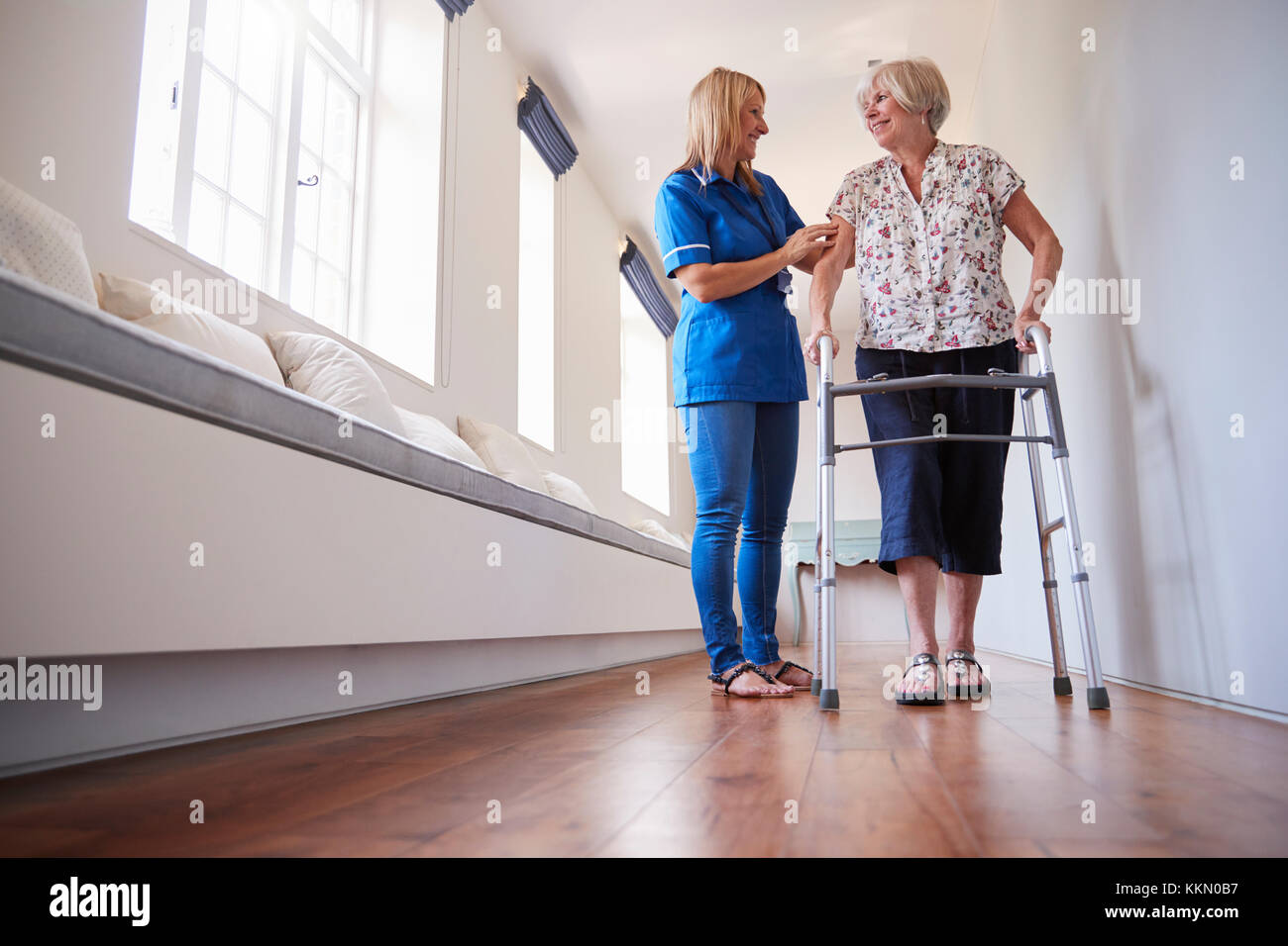 L'infermiera aiutando donna senior di utilizzare un telaio a piedi a piena lunghezza Foto Stock