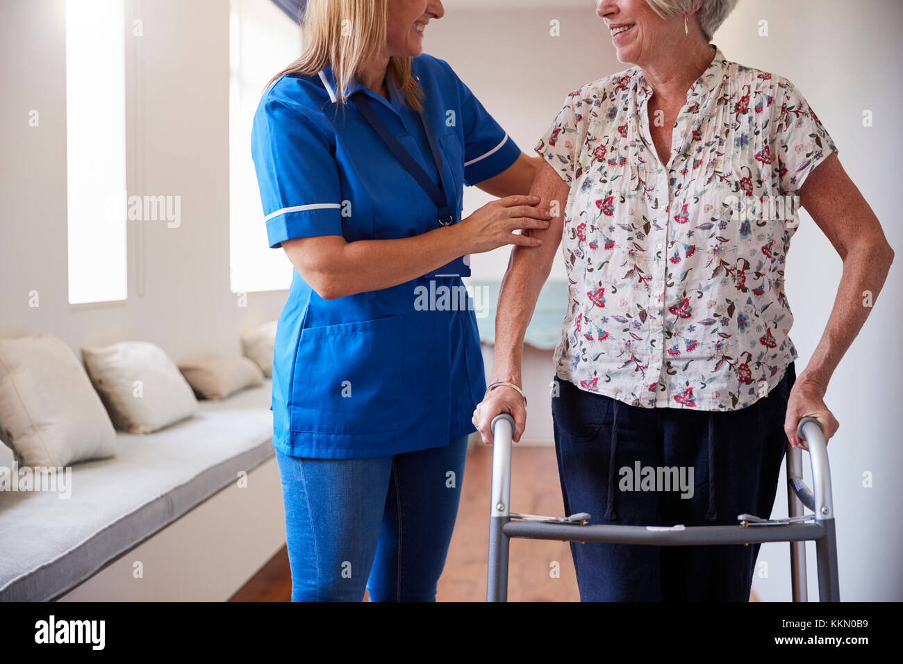 L'infermiera aiutando donna senior di utilizzare un telaio a piedi, metà sezione Foto Stock