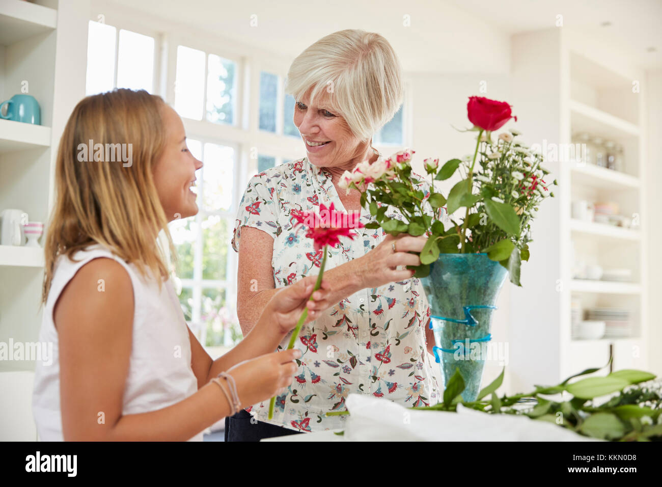 Senior donna disponendo dei fiori con il nipote a casa Foto Stock
