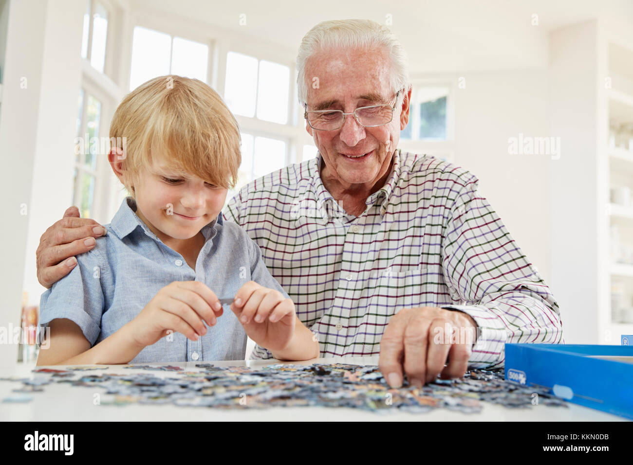 Uomo Senior e nipote di fare un puzzle a casa Foto Stock