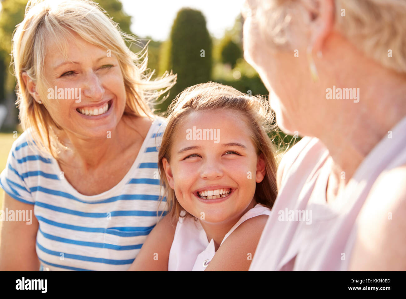Tre generazioni femminili della famiglia seduti in un giardino Foto Stock