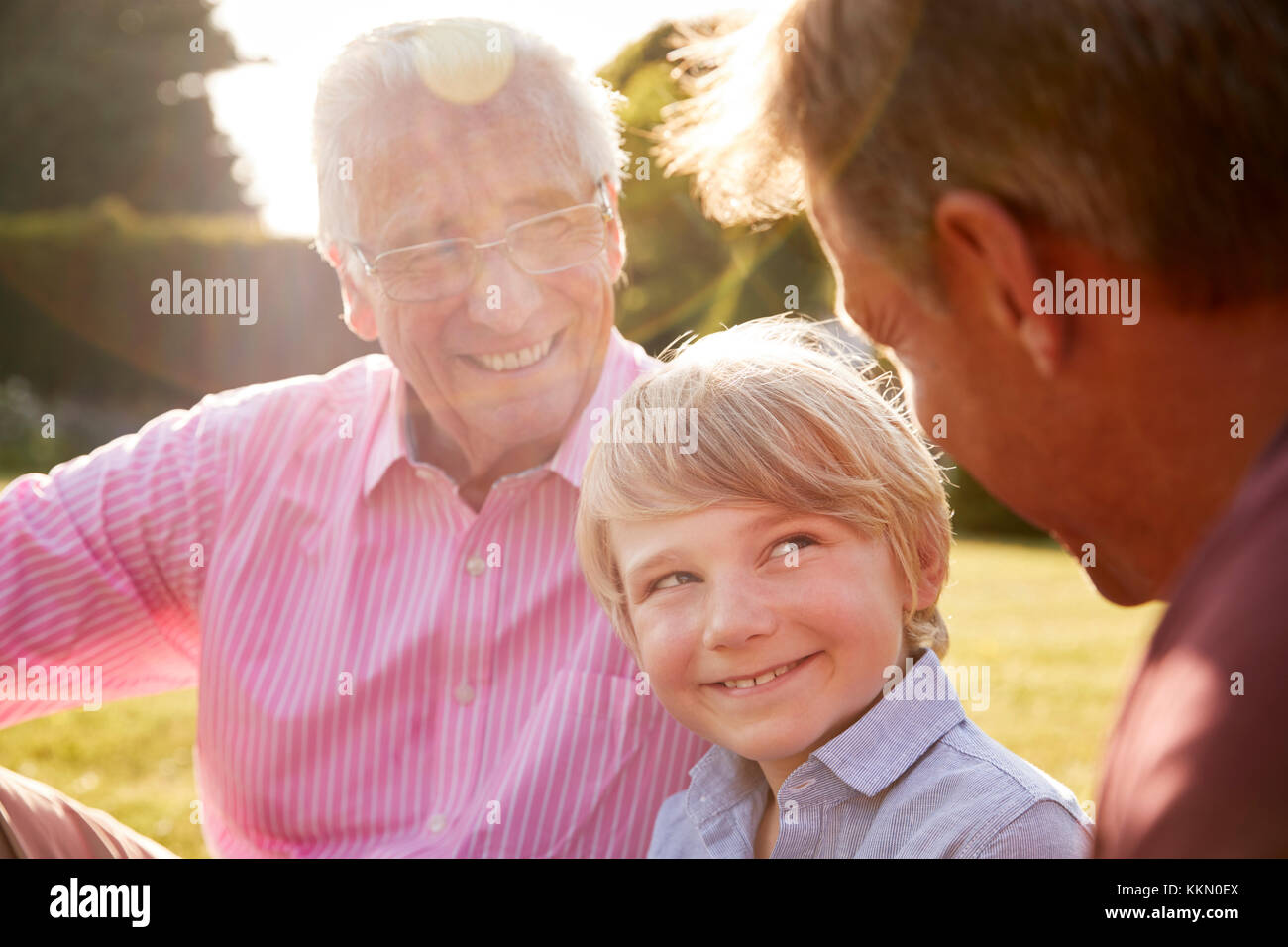 Maschio di tre generazioni di una famiglia seduti in un giardino Foto Stock