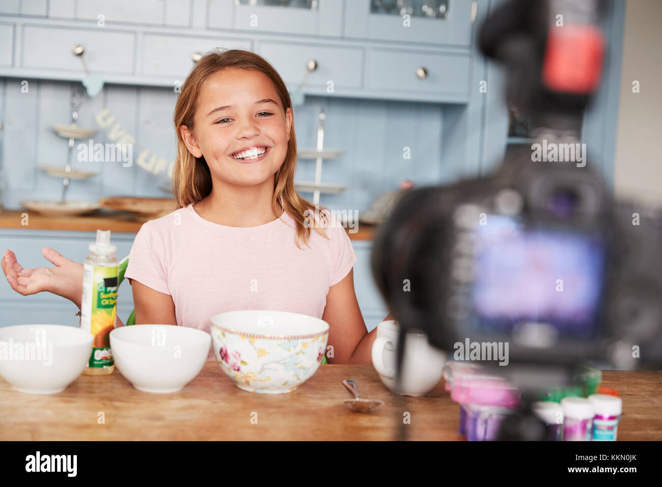 Pre-teen girl blog video in cucina sorride alla telecamera Foto Stock