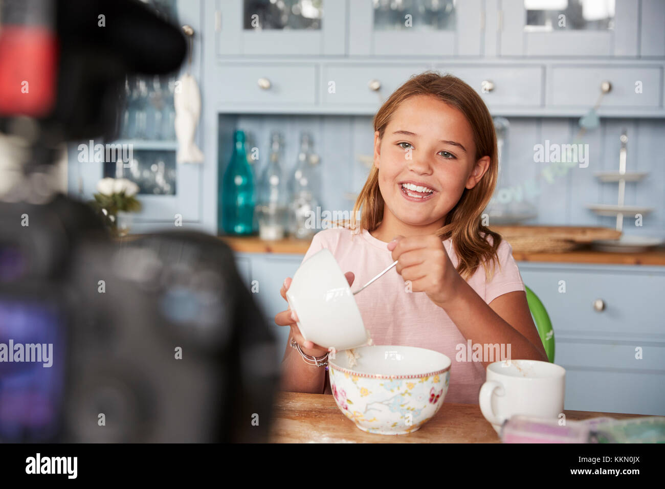 Pre-teen girl blog video in cucina ingredienti di miscelazione Foto Stock