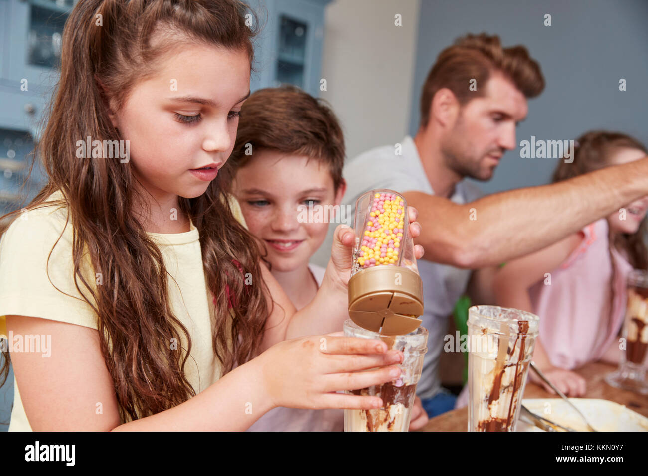 Padre produrre gelati sundaes con i bambini a casa Foto Stock