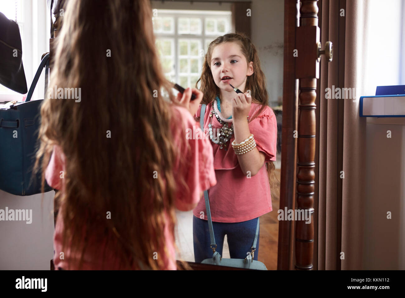 Ragazza giovane giocare vestire il gioco nella parte anteriore dello specchio a casa Foto Stock